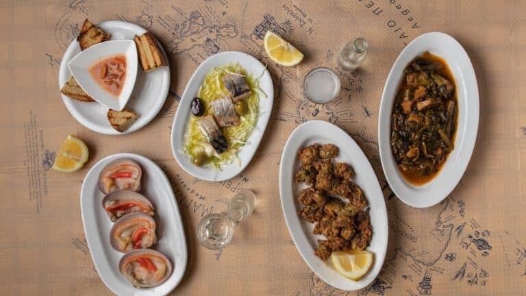 Sélection typique de mezedes de la mer servis traditionnellement dans un tsipouradiko de la région de Volos, ici Demiris à Volos. Coques charnues (Γυαλιστερές), Anémones de mer frites (Κολιτσιάνοι), Seiches aux épinards (Σουπιές με σπανάκι), Poissons marinés / salés (Λακέρδα ή παστό ψάρι), Pain grillé et tartinade et Le Tsipouro au centre